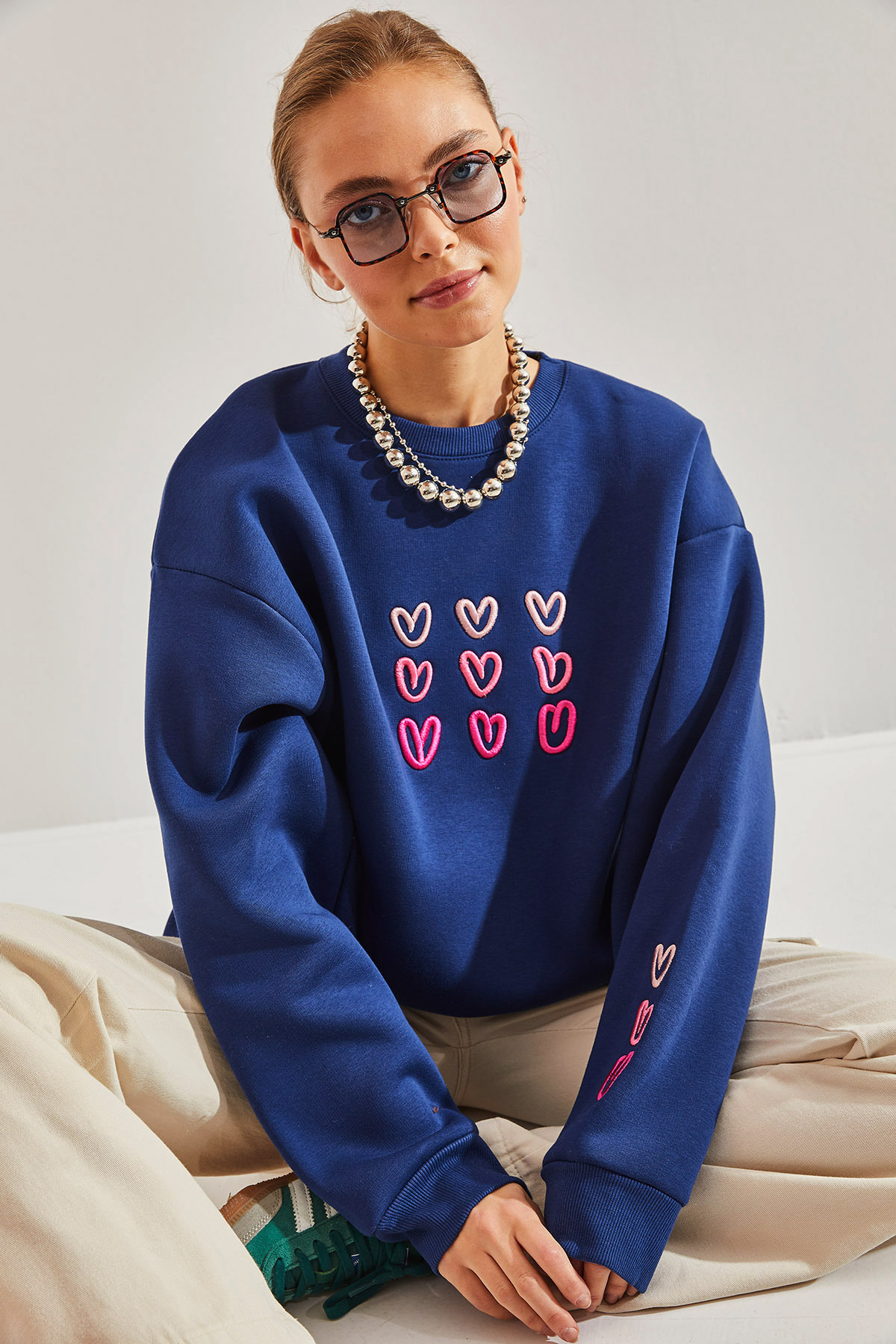  Nasza nowa bluza w kolorze granatowym to połączenie romantyzmu i wygody. Delikatne różowe, haftowane serca na miękkiej, bawełnianej tkaninie tworzą wyjątkową kompozycję. Oversizowy krój i przyjemny meszek wewnątrz zapewnią Ci ciepło i komfort