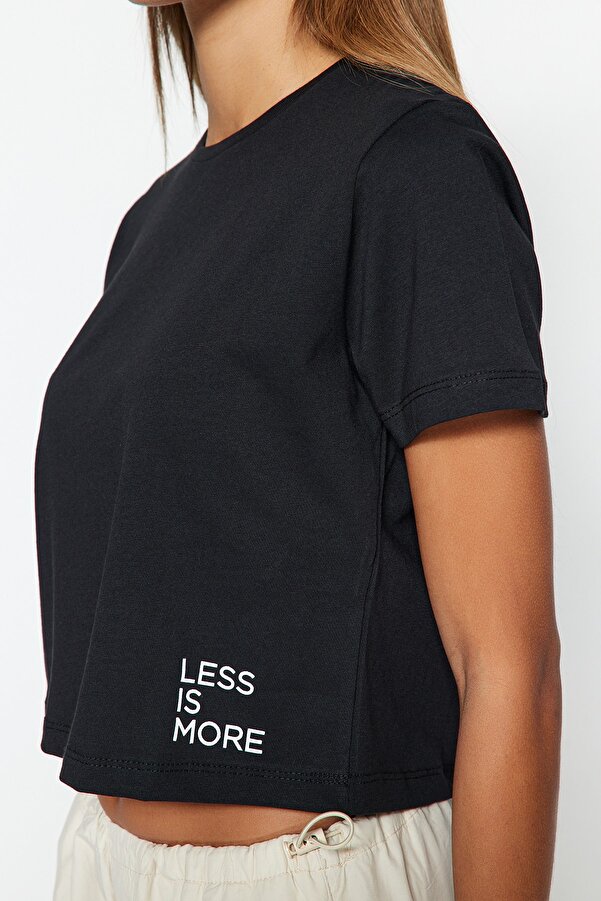 krótki top w kolorze czerni to idealne rozwiązanie. Wykonany z miękkiej bawełny, doskonale sprawdzi się podczas treningów, spacerów czy spotkań z przyjaciółmi. Mały biały napis „Less is more” to subtelny akcent, który dodaje charakteru.